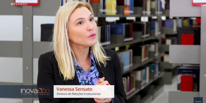 Vanessa Sensato, diretora de relações institucionais, concedendo entrevista para a Record dentro de uma biblioteca