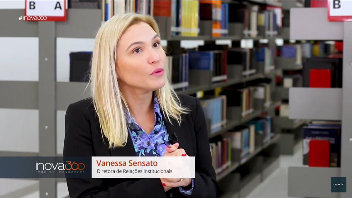 Vanessa Sensato, diretora de relações institucionais, concedendo entrevista para a Record dentro de uma biblioteca
