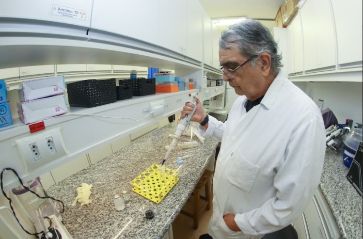 Professor Duran no laboratório. Ele é branco, tem mais de 60 anos, cabelos grisalhos e veste jaleco.