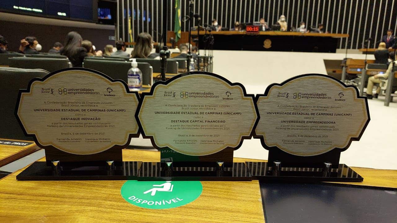A imagem mostra os três troféus que a Unicamp ganhou em cima de uma mesa. 