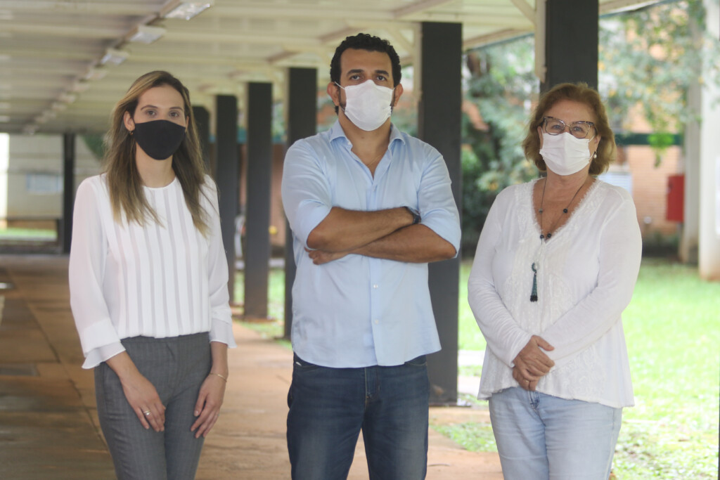 Tinta anti-covid: Os três pesquisadores estão lado a lado de camisas claras, ao fundo corredor da universidade