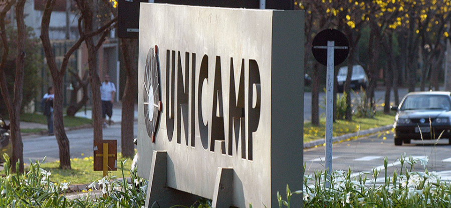 Foto focada na placa da Unicamp na entrada do campus de campinas. em um dia ensolarado. Fim da descrição