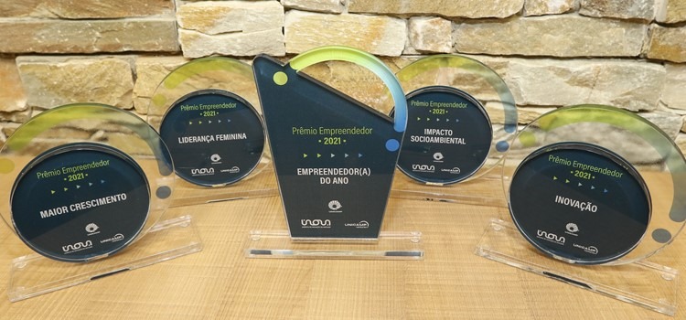 Foto de 5 troféus, sendo quatro redondos e um retangular maior. Está escrito em todos Prêmio Empreendedor e logos da Inova, Unicamp e Unicamp Ventures