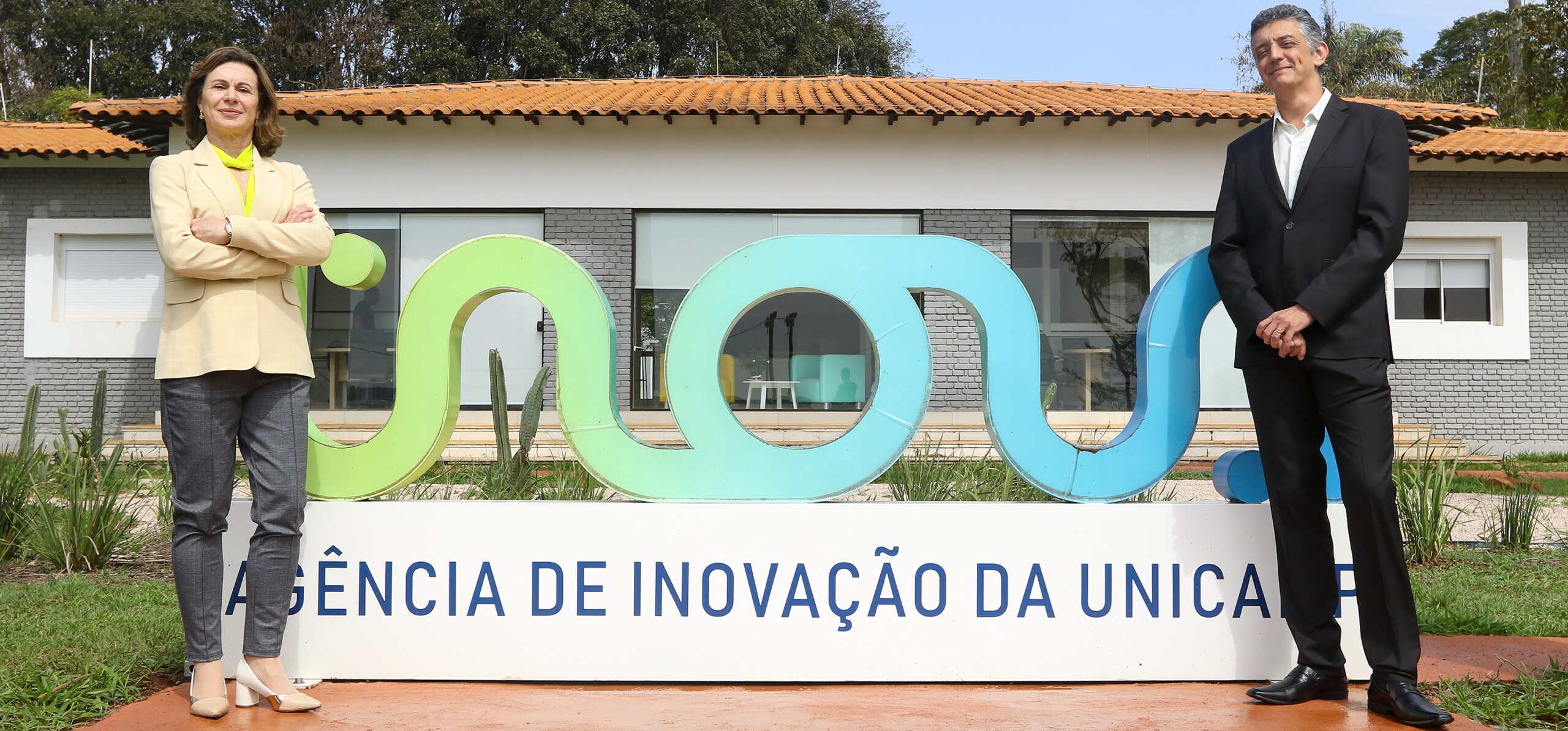 Foto do logo da Inova Unicamp com a professora Ana Frattini e o professor Renato Lopes nas pontas