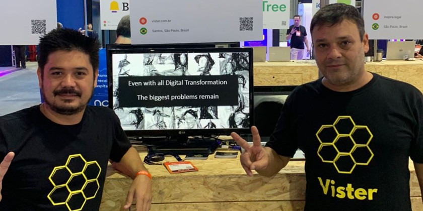 Dois homens brancos usando camisa preta escrito "Vister", nome da marca que está no fundo da imagem, Uma fintech com um modelo de crédito inovador