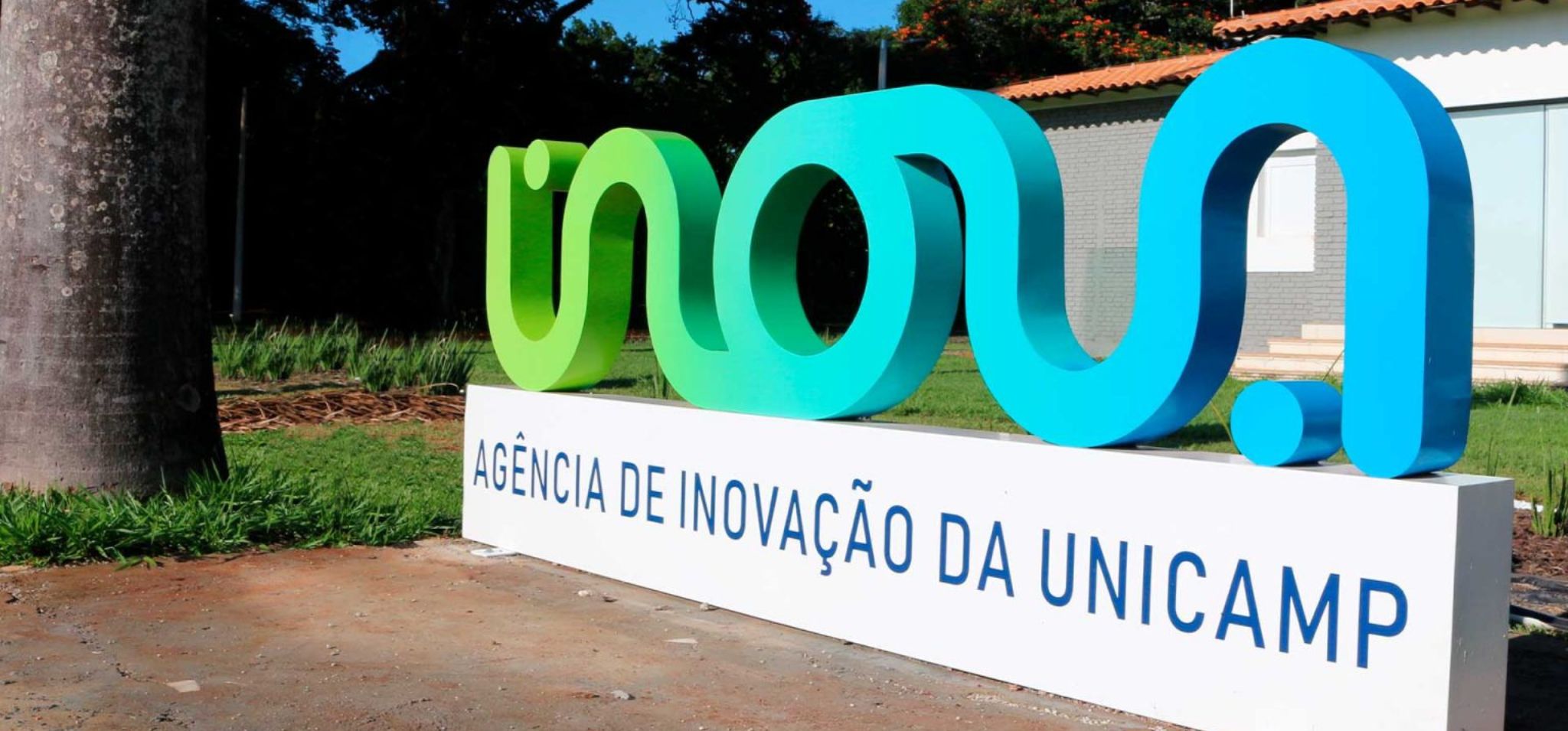 Monumento do Inova, escrito agência de inovação da Unicamp com uma casa ao fundo
