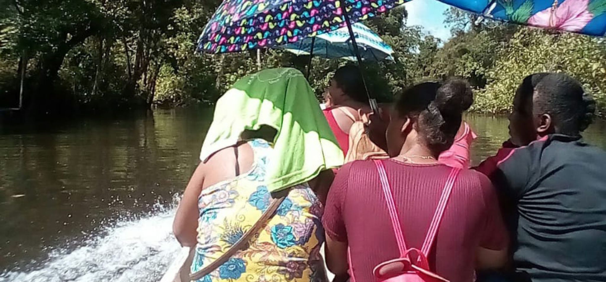 Pessoas segurando um guarda-chuva para se proteger do sol enquanto navegam em uma canoa