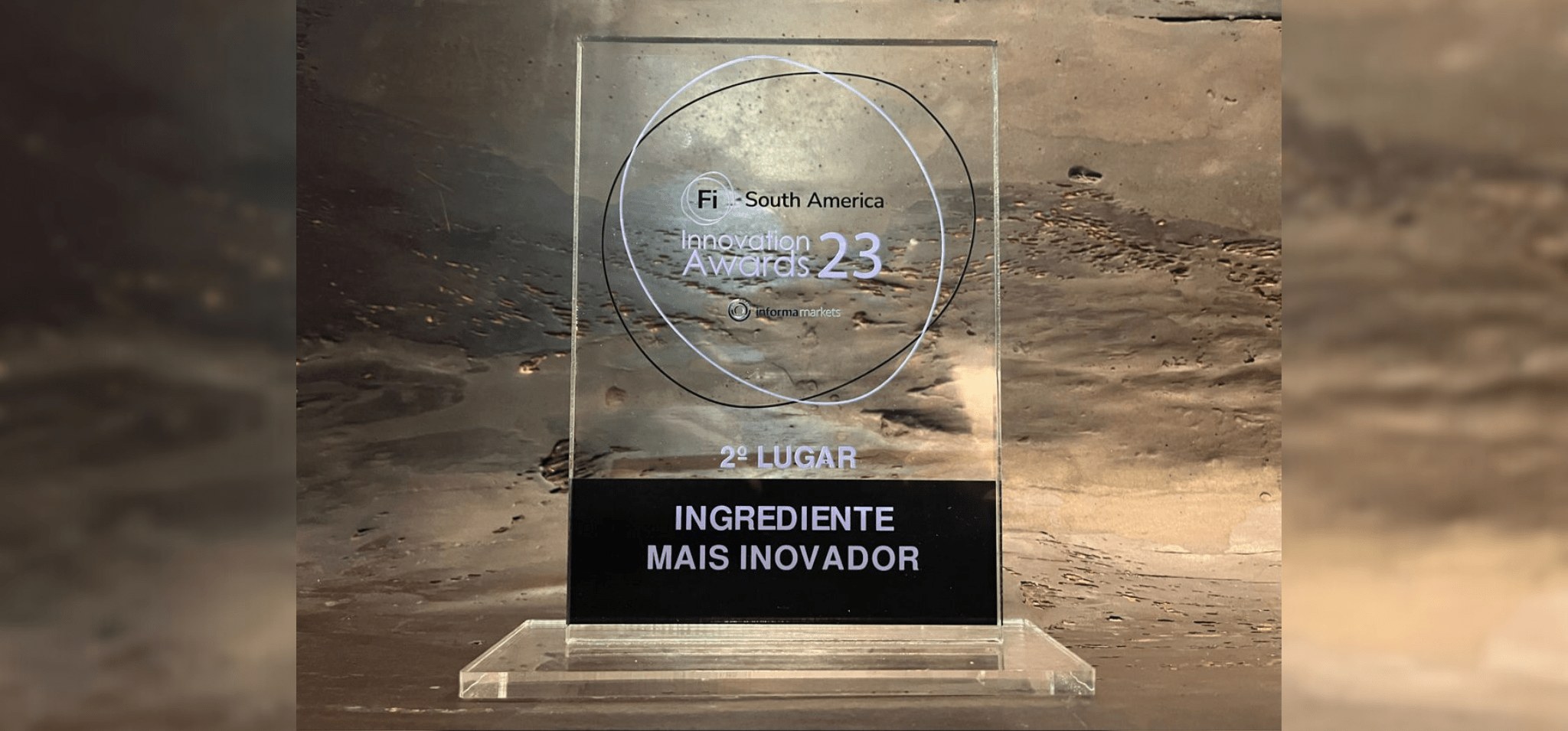 Troféu de acrílico com o nome do prêmio, a colocação (2º lugar) e a categoria (Ingrediente mais inovador). Fim da descrição