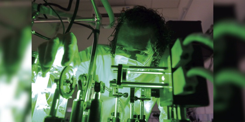 Fotografia de Professor Luiz Fernando Zagonel, ele está iluimionado por uma luz esverdeada em um laboratório, mexe em equipamentos. Fim da descrição.